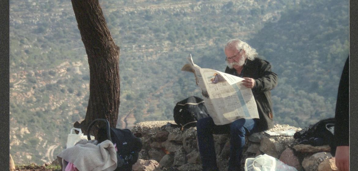 Adel Tartir under a tree reading a newspaper. Photo: www.adeltartir.com