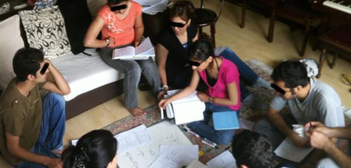 Studierende des Bahá’í Institute for Higher Education bilden sich heimlich im Wohnzimmer weiter (2009). Foto: Niknaz Aftahi. via Wikimedia Commons (https://commons.wikimedia.org/wiki/File%3AIranian_BIHE_students_in_a_living_room.jpg). Lizenz: CC BY-SA 4.0
