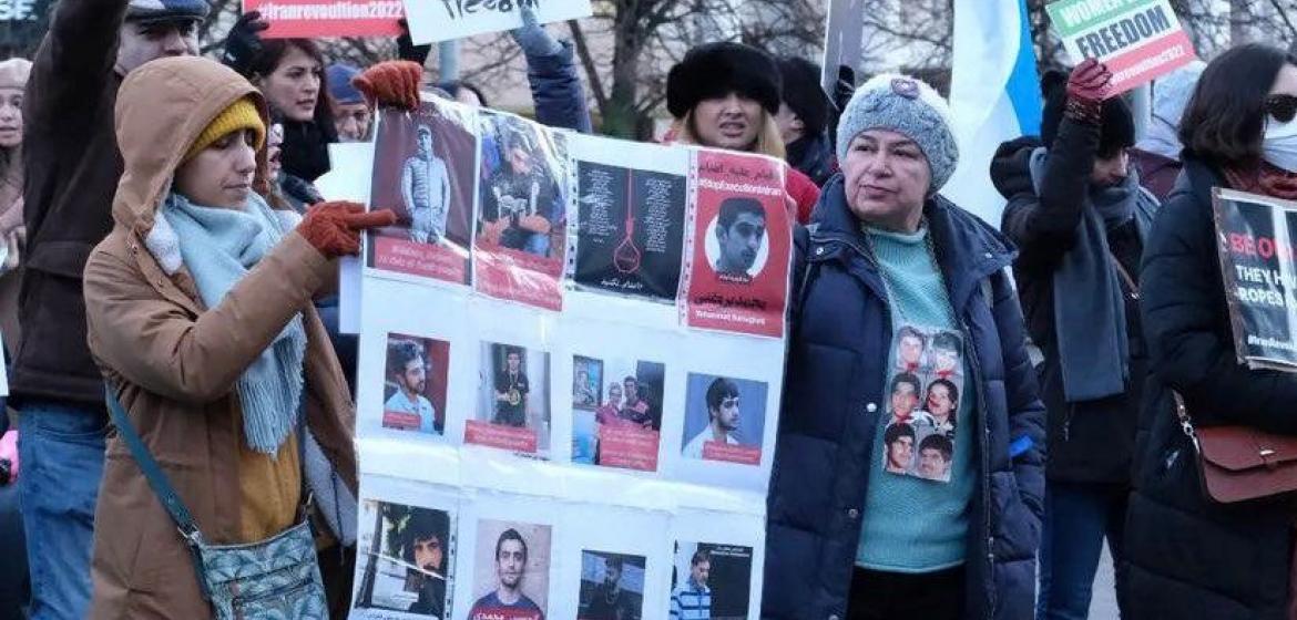 Mansoureh Behkish demonstriert gegen die Hinrichtung von Demonstrant:innen, Dublin 2022. Auf einem Plakat um ihren Hals sind Bilder ihrer Familienmitglieder zu sehen, die während der berüchtigten 1980er-Jahre in Iran gehängt oder getötet wurden. Foto: Mansoureh Behkish, privat