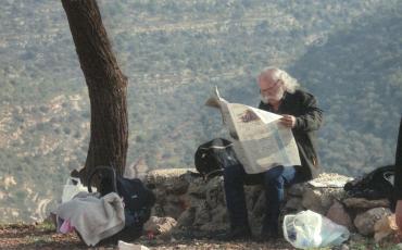Adel Tartir under a tree reading a newspaper. Photo: www.adeltartir.com