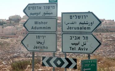 Jerusalem wird auf Arabisch in zwei Varianten wiedergegeben, dem gebräuchlichen al-Quds in Klammern und der direkten Transkription aus dem Hebräischen. Bildquelle: https://de.wikipedia.org/wiki/Datei:Hebrew_Arabic_English_road_signs.jpg