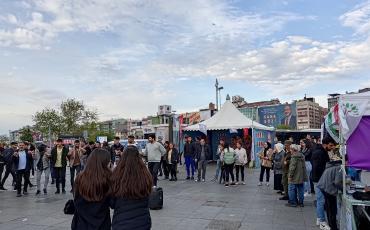 Wahlkampf 2023: Im Vordergrund tanzen Menschen vor dem Stand der Yeşil Sol Partei. Im Hintergrund ist Kemal Kılıçdaroğlu auf einer Hauswand zu sehen. Foto: Kinan Alzouabi