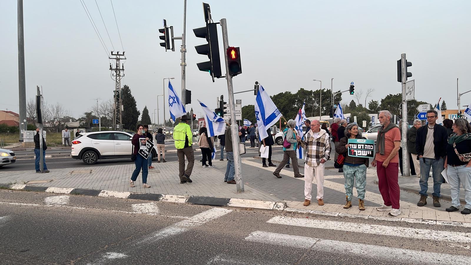 Bild von der Karkur-Kreuzung, auf dem Schild der Frau in der Mitte steht „Wie viel Blut wird noch vergossen werden?”, in der linken Bildhälfte eine Demonstrantin mit dem Bild eines Kindes, das im Libanon durch israelische Angriffe getötet wurde. Foto: Private Aufnahme des Autors.